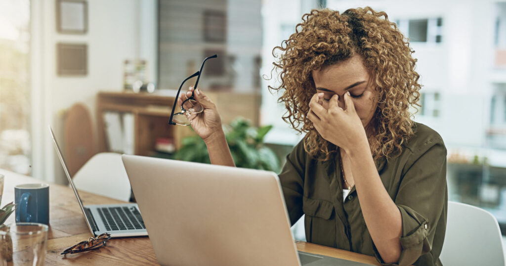 Shot of a young woman suffering from anxiety while using a computer at her work desk.